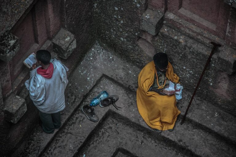 Underground church in Axum, Ethiopia, with locals praying near historical architectural details.