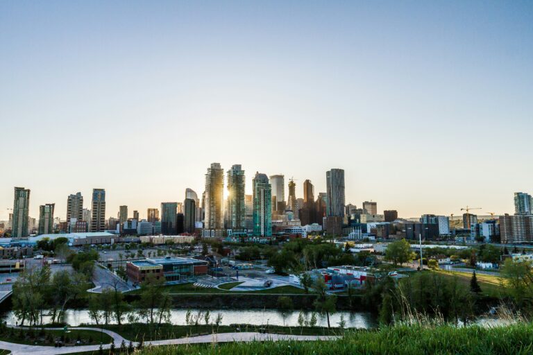 Panoramic photo of downtown Calgary with tall buildings lit by sunset glow.
