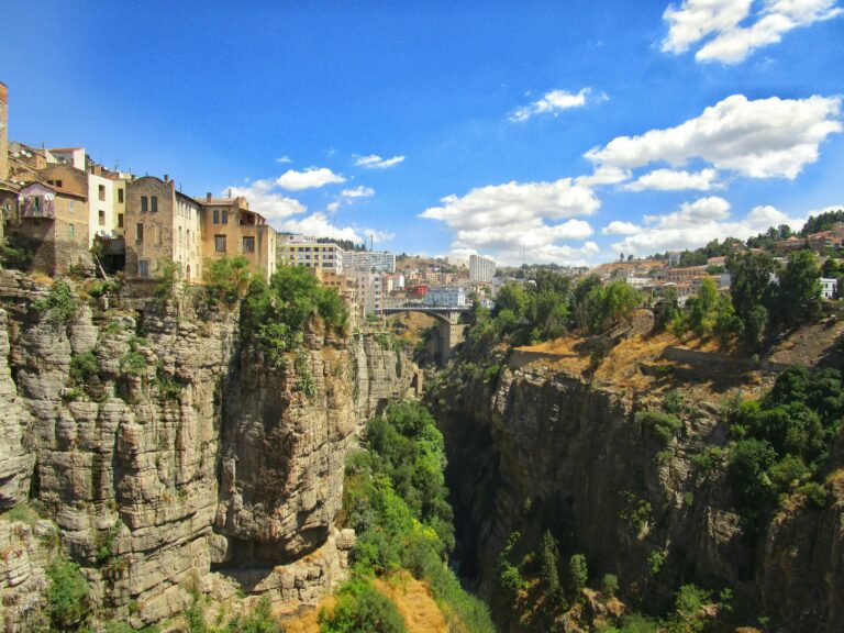 Cliffs and historic buildings in Constantine, Algeria, under a blue sky.