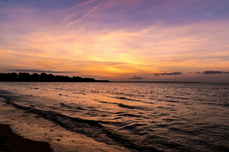 Apus de soare pe plaja cu valuri ușoare în Darwin, Australia.