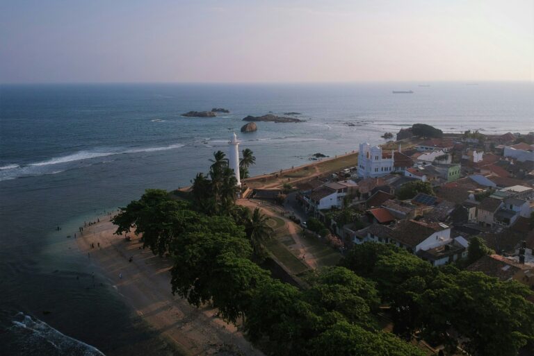 Vedere aeriană a farului și a coastei din Galle, Sri Lanka, cu valuri și case istorice.