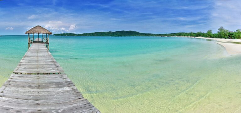 A wooden pier stretching into the clear waters of Koh Rong Island, Cambodia, with stunning scenery and a tropical beach.