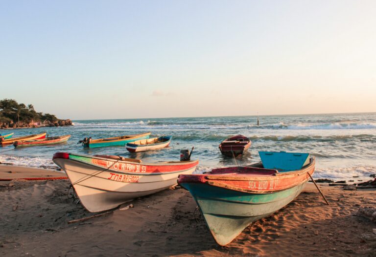 Bărci de pescuit colorate pe o plajă din Jamaica la apus