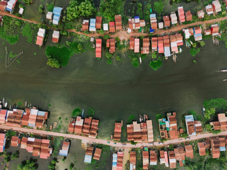 Vedere aeriană a satului plutitor de pe Tonlé Sap Lake, cu case colorate, apă liniștită și vegetație verde.