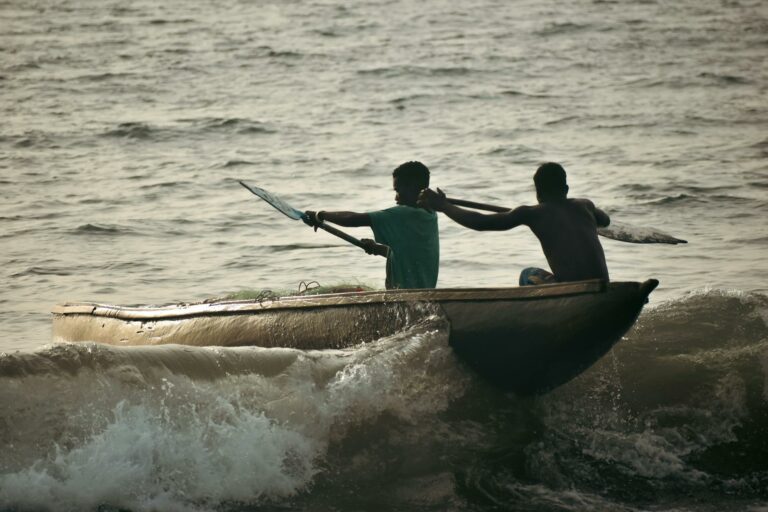 Pescari din Liberia într-o barcă pe valuri la apus