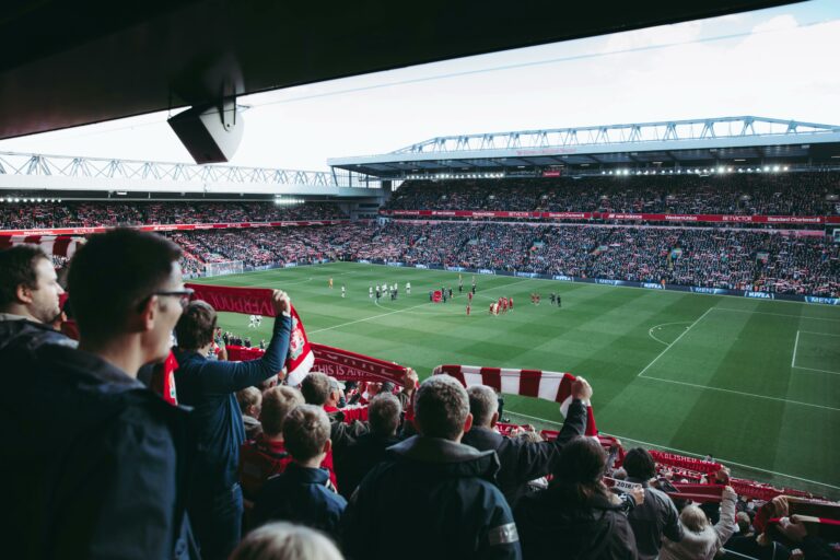 Anfield Stadium in Liverpool with fans waving scarves and supporting the local team.