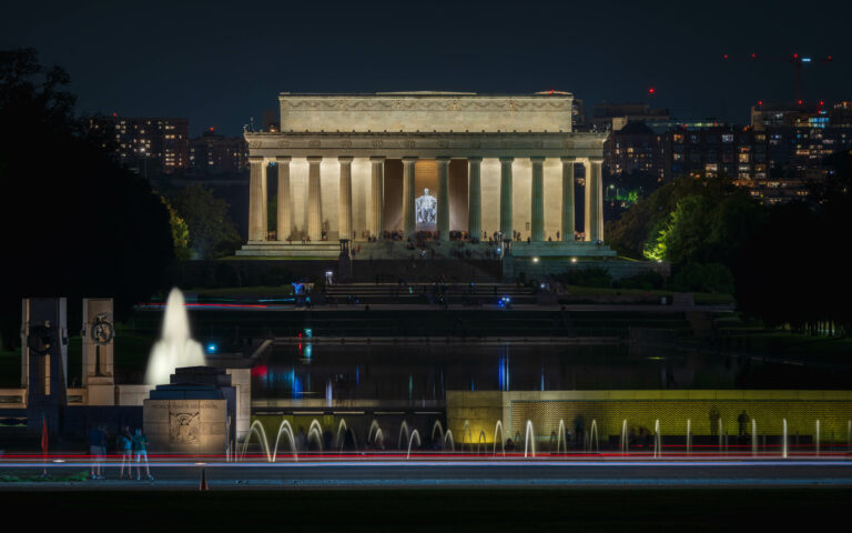 Memorialul Lincoln din Washington D.C., iluminat noaptea, cu fântâni decorative în prim-plan.