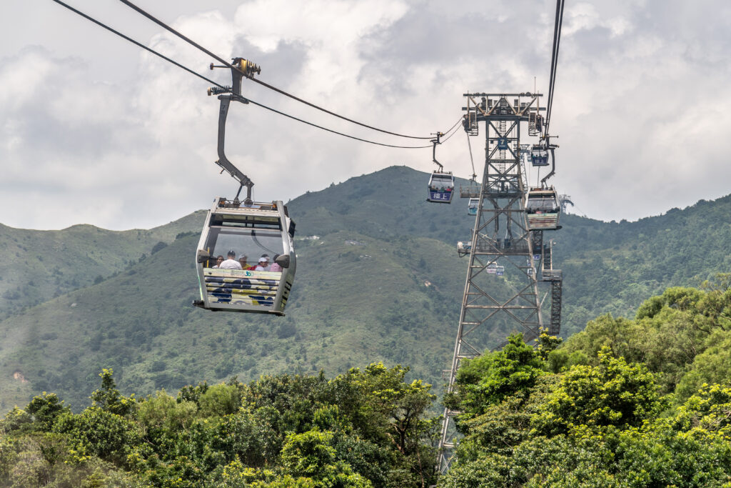 Ngong Ping 360, sistem de telecabine panoramice în Hong Kong, cu munți în fundal.