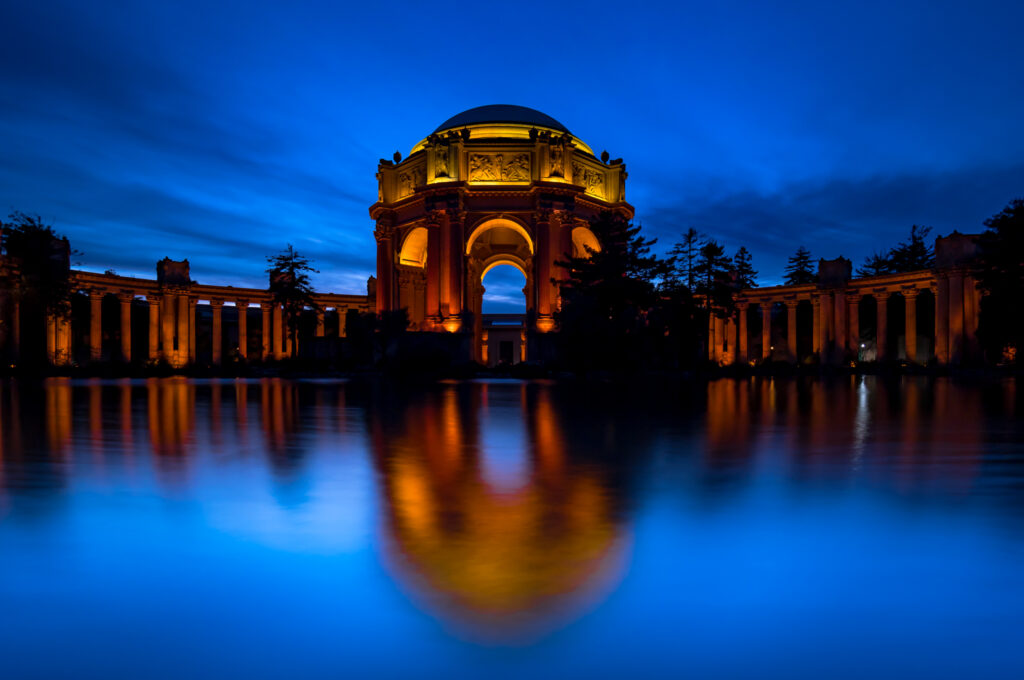 Imaginea Palatului Artelor Frumoase iluminat pe timp de noapte, reflectat în apă, San Francisco.
