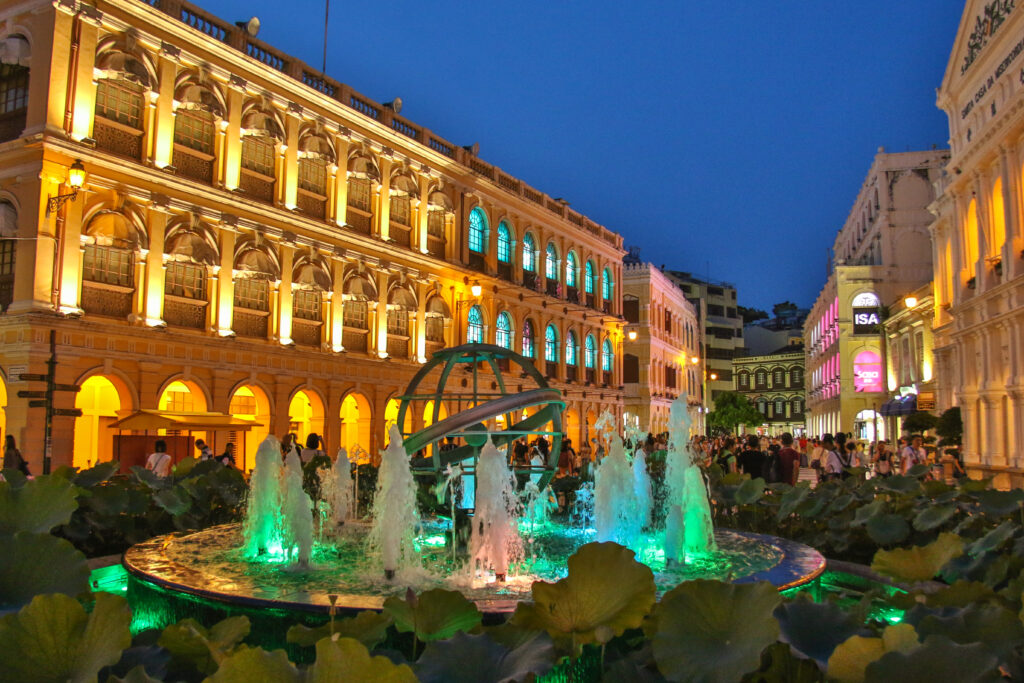 Imagine a Praça do Senado în Macau, cu iluminare nocturnă și fântână decorativă, atracție turistică iconică.