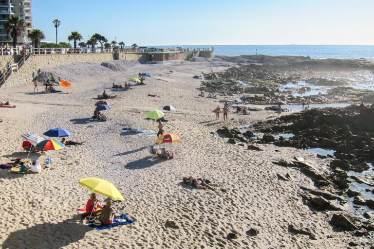 Plaja Camps Bay, Cape Town, cu umbrele colorate și nisip alb, loc popular pentru turiști.