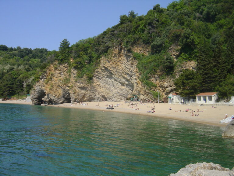 Imagine cu Plaja Mogren din Budva, cu stânci spectaculoase și țărm nisipos, o destinație de vis pentru turiști.