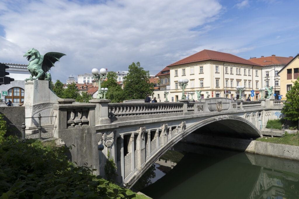 Imagine cu Podul Dragonilor din Ljubljana, cu statui de dragoni și atmosferă urbană.