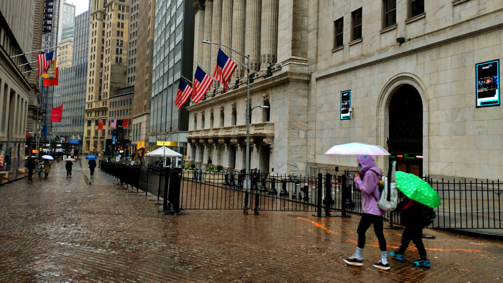 Wall Street din New York, clădiri simbolice și umbrelă într-o zi ploioasă.
