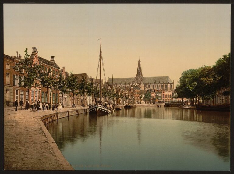 Chiesa Grande di Haarlem vista lungo un canale con case e vegetazione circostante.