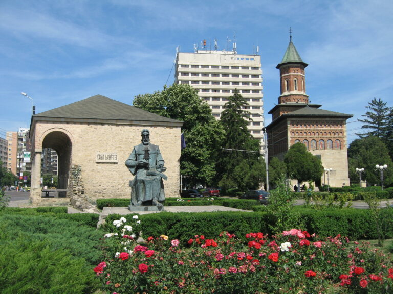 Casa Dosoftei di Iași circondata da fiori e statue, una destinazione storica popolare.