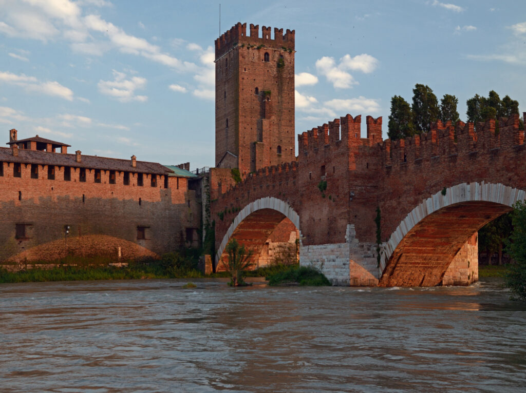 Foto del Castelvecchio di Verona con il ponte fortificato e la torre nella luce calda del tramonto.