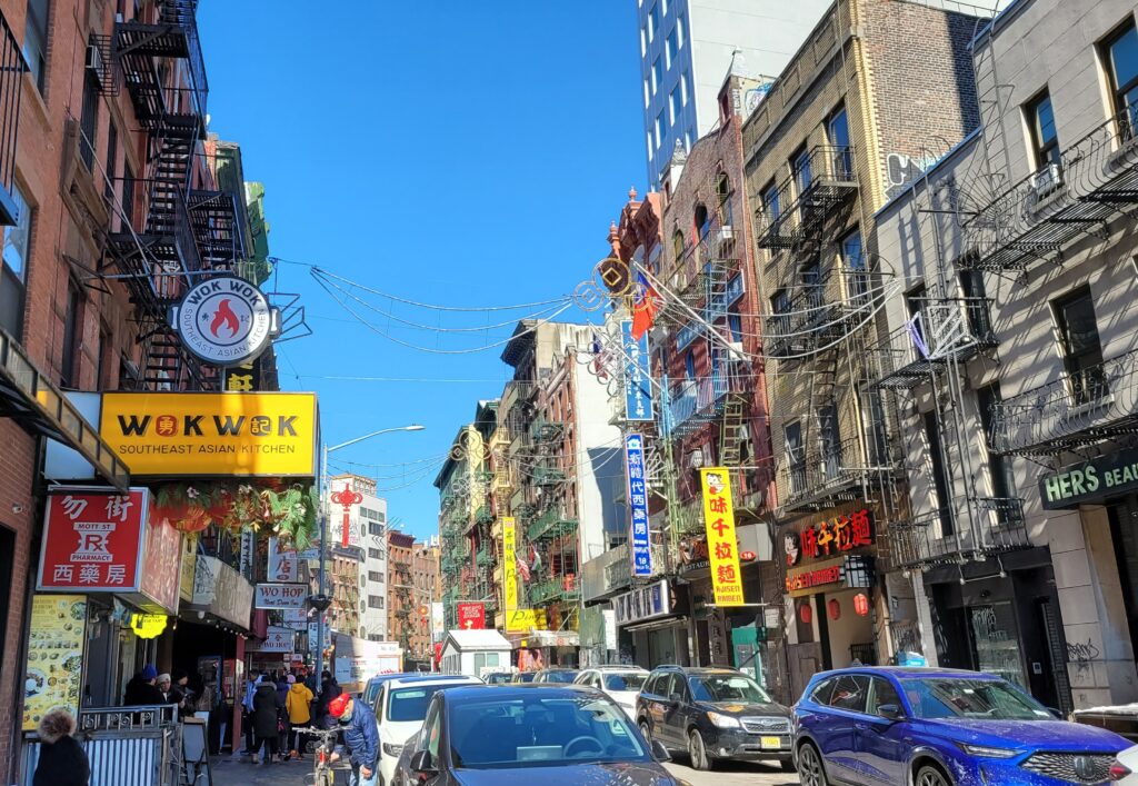 Chinatown New York, facciate di edifici tradizionali e insegne in una strada affollata.