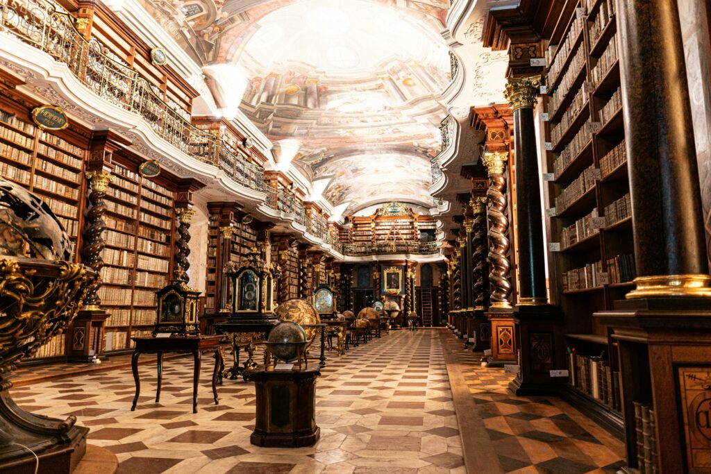 Biblioteca Națională Klementinum din Praga, vedere de interior cu tavane pictate și rafturi cu cărți.