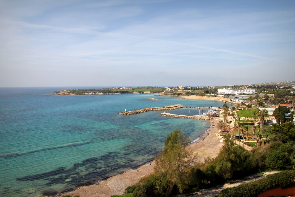 Vedere panoramică a plajei Coral Bay Paphos, cu ape albastre și peisaj natural minunat.