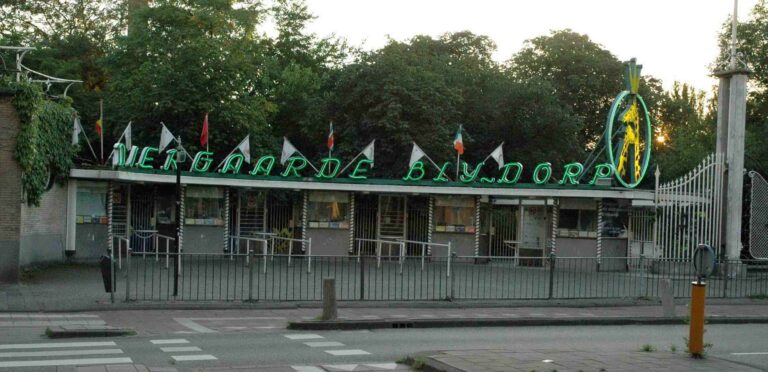 Ingresso principale dello Zoo di Rotterdam con luci al neon e bandiere.