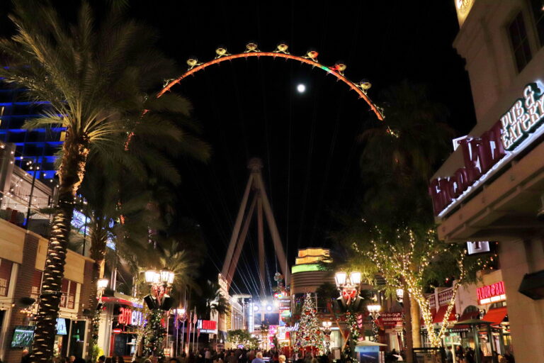 High Roller Las Vegas illuminato di notte, circondato da palme e edifici vibranti.