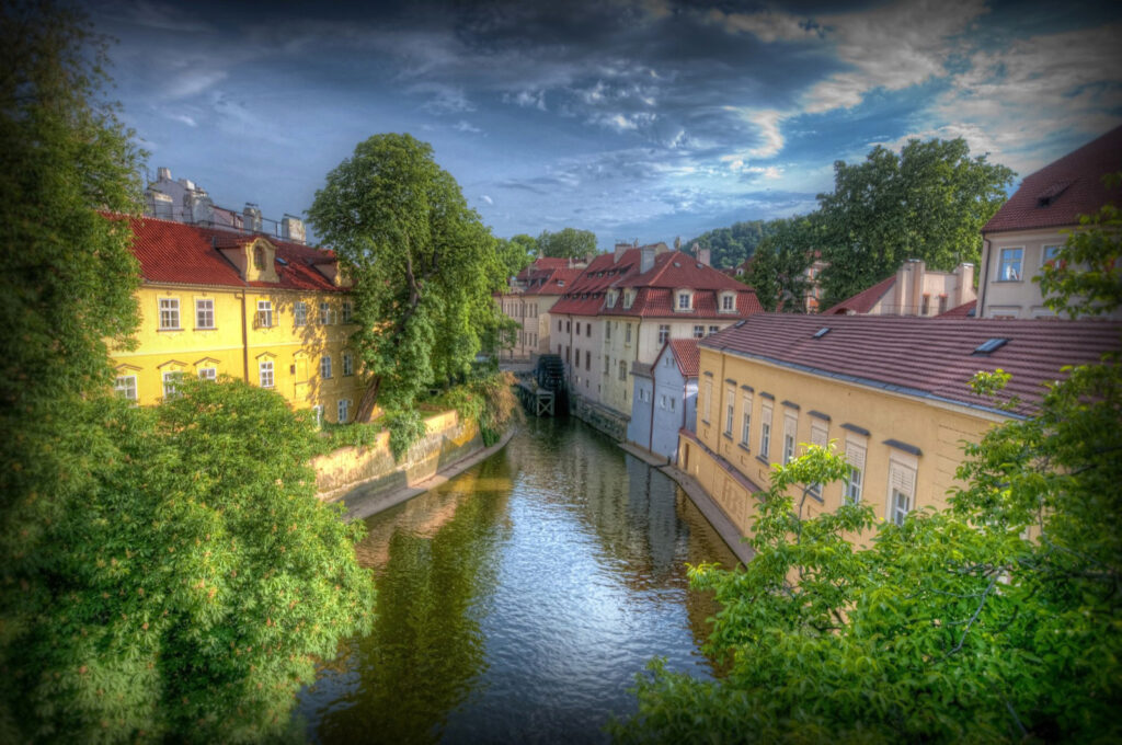 Peisaj pitoresc al Insulei Kampa din Praga, cu arhitectură de pe malul apei și natură frumoasă.