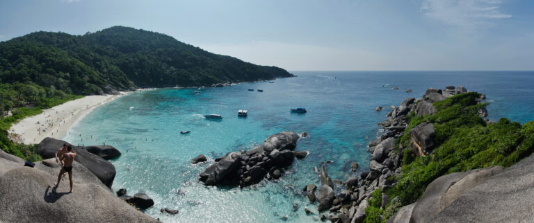 Paesaggio delle isole Similan con spiaggia, rocce, vegetazione e barche su acque turchesi.