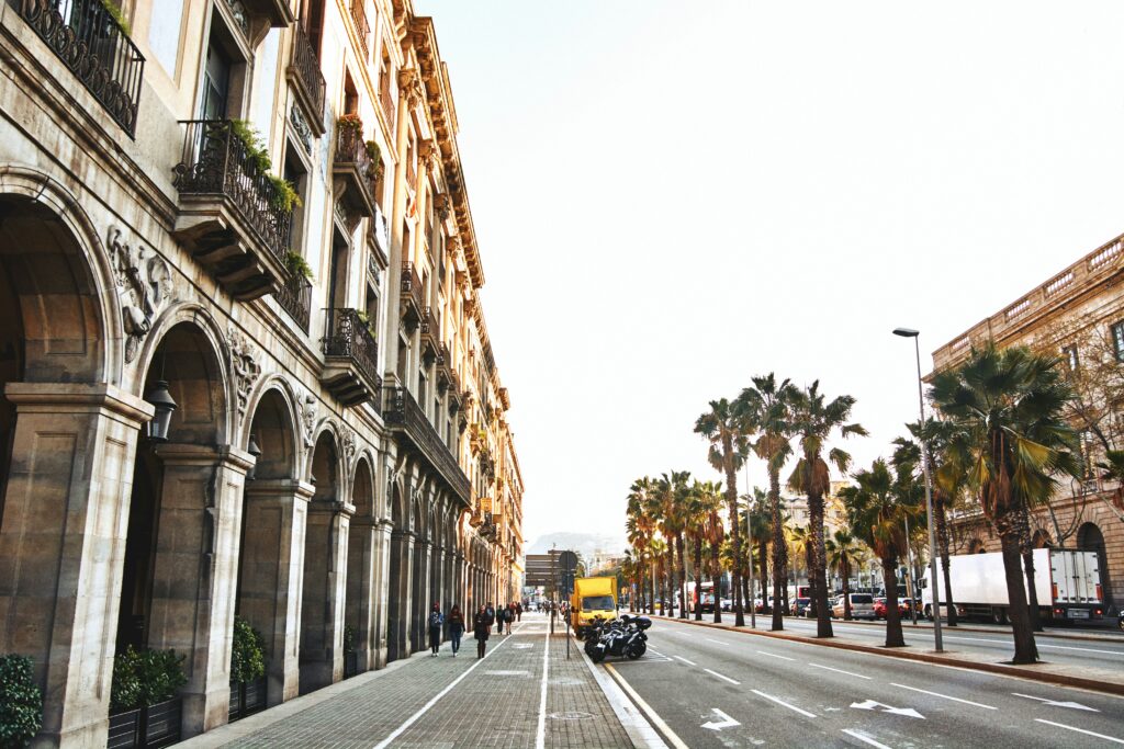 Strada La Rambla din Barcelona, cu palmieri și clădiri istorice.