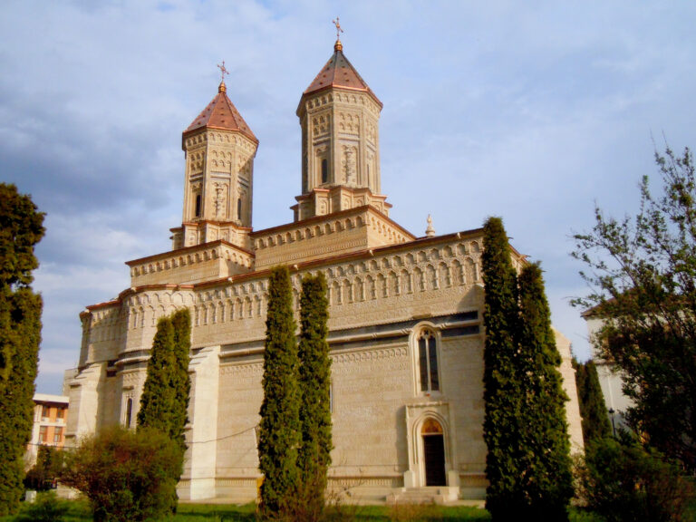 Vista frontale del Monastero dei Tre Gerarchi di Iași sotto cieli limpidi, con dettagli architettonici impressionanti.