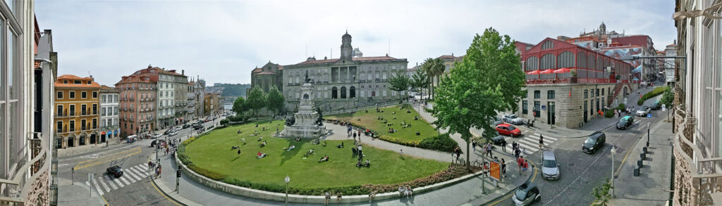 Palazzo della Borsa di Porto e la piazza davanti con persone che si rilassano sull'erba.