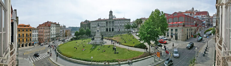 Palazzo della Borsa di Porto e la piazza davanti con persone che si rilassano sull'erba.