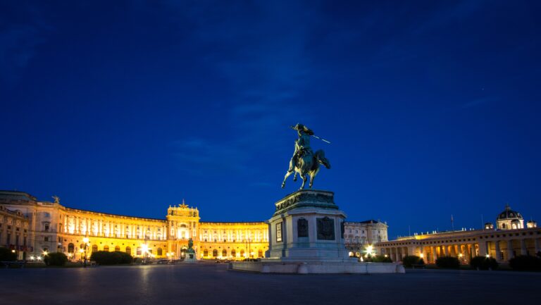 Palatul Hofburg din Viena iluminat noaptea cu statuia în prim-plan.