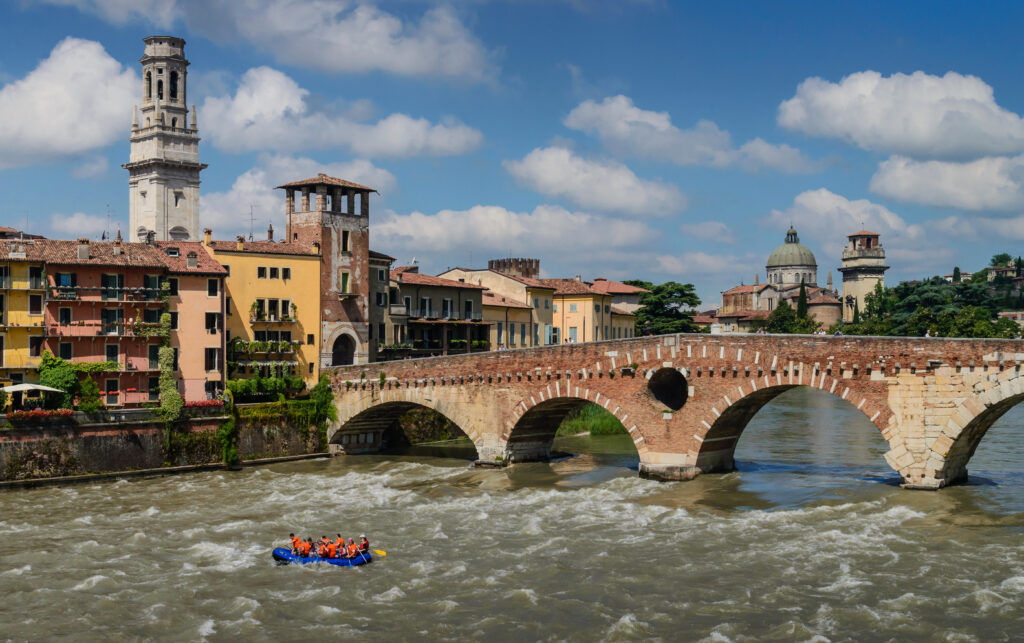 Ponte Pietra a Verona con atmosfera soleggiata e edifici storici, fiume Adige che scorre sotto.