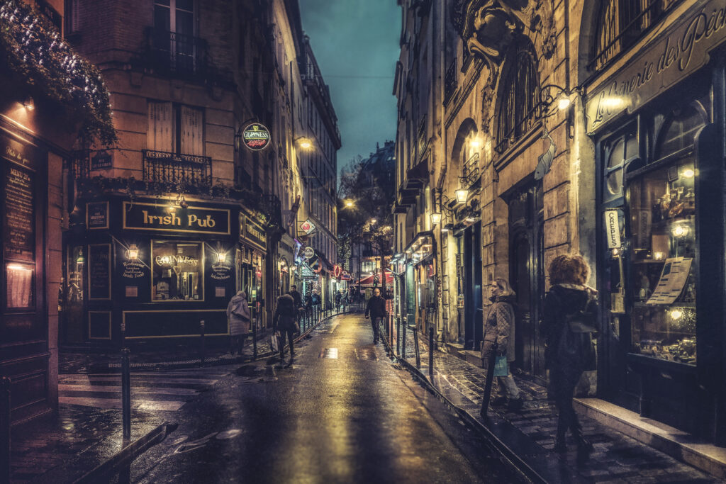 Stradă iluminată seara în Quartier Latin, Paris, cu pub-uri și restaurante.