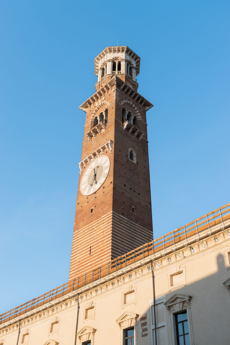 Torre dei Lamberti a Verona, fotografata con cielo blu, evidenziando i dettagli architettonici.