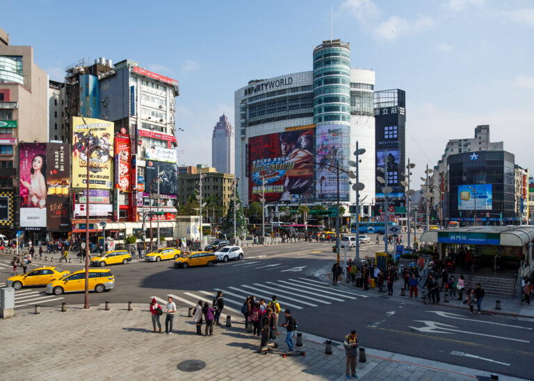 Immagine di Ximending Taipei, area vibrante con edifici moderni, pubblicità luminose e taxi gialli in movimento.